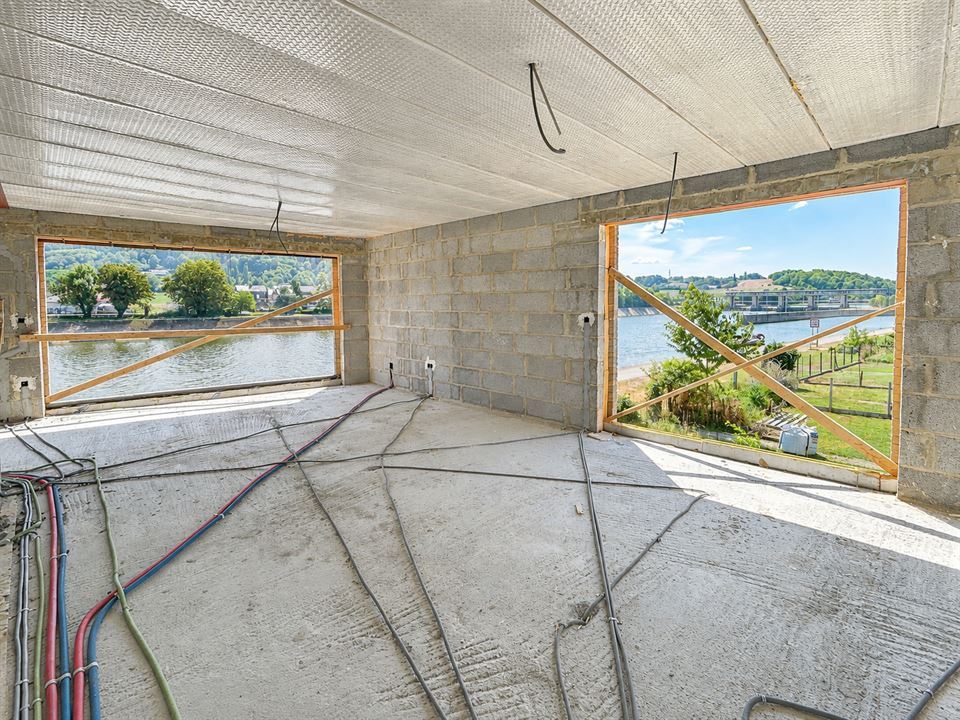 Intérieur d'un appartement en chantier, avec vue sur la Meuse par les baies vitrées